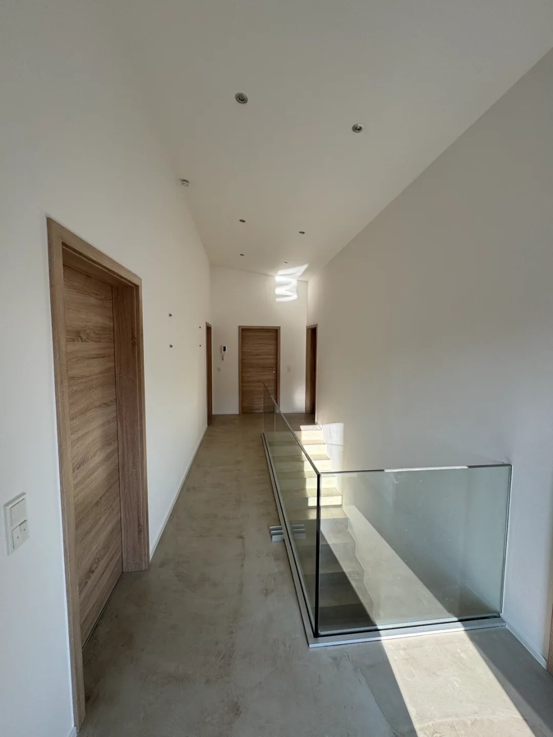 Heller Flur mit Treppe und Glasgeländer in Schmelz – Malerbetrieb Mergenthaler im Saarland