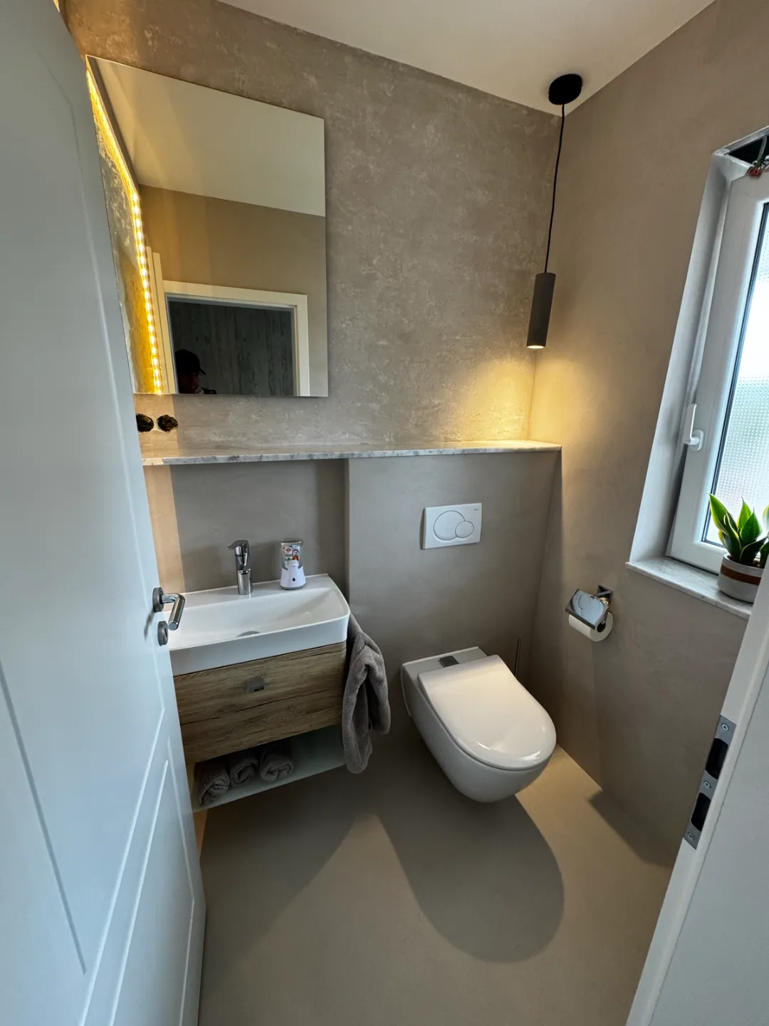 Gäste-WC mit fugenloser Wandfläche in Beige und indirektem Licht – Malerbetrieb Mergenthaler im Saarland