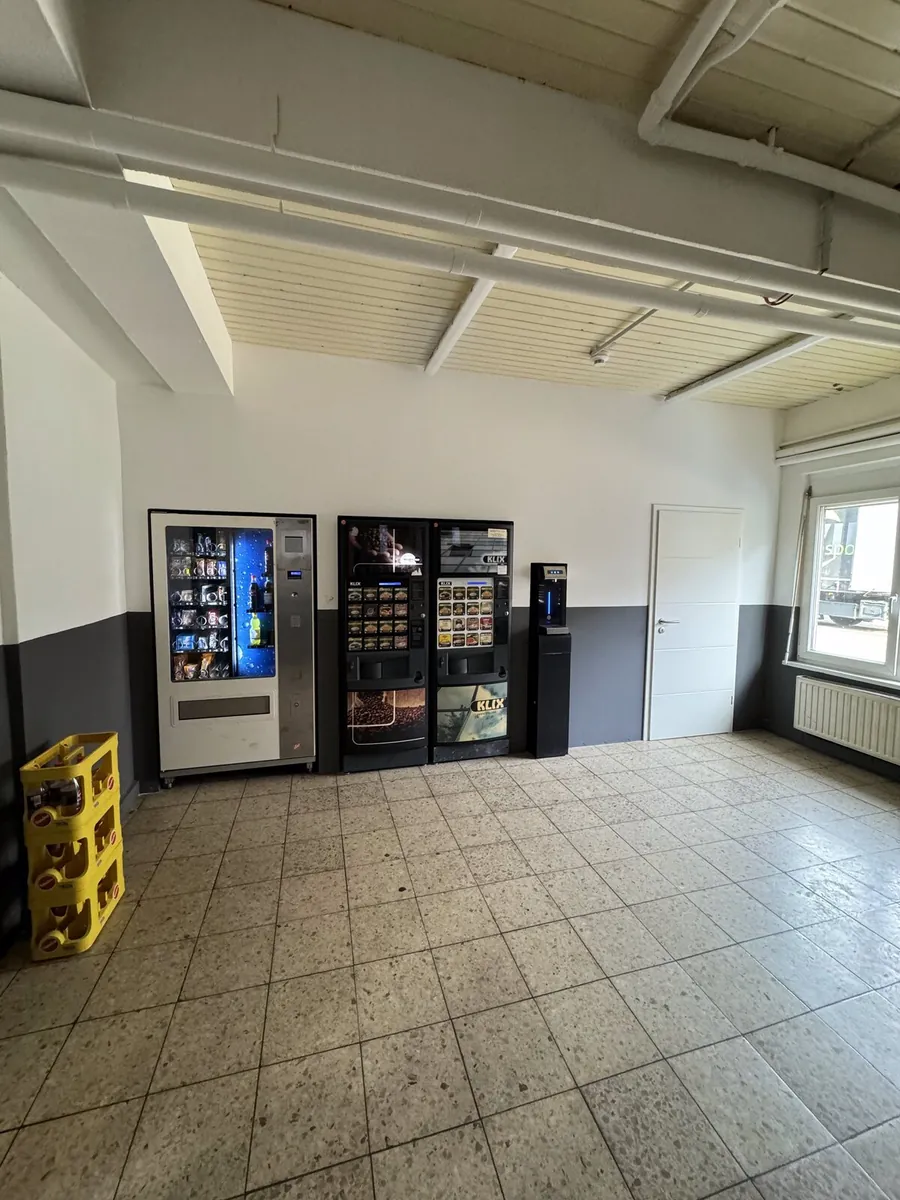 Vorraum in Homburg nachher: neu gestrichene helle Wände mit grauem Sockelband, Trockenbauwand für die Snackautomaten