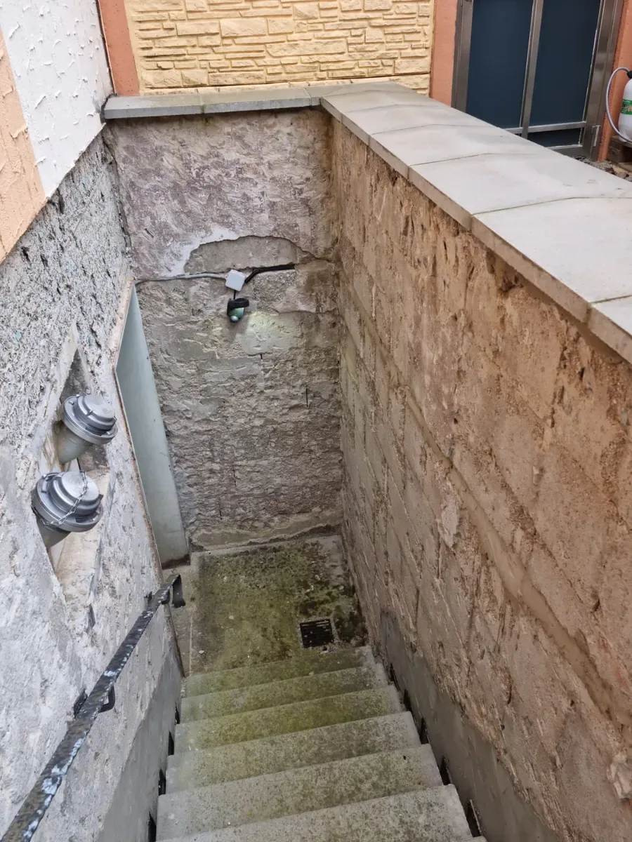 Kellerabgang in Hüttigweiler vor der Sanierung: Treppe und Außenwände mit Verschmutzung und Putzschäden