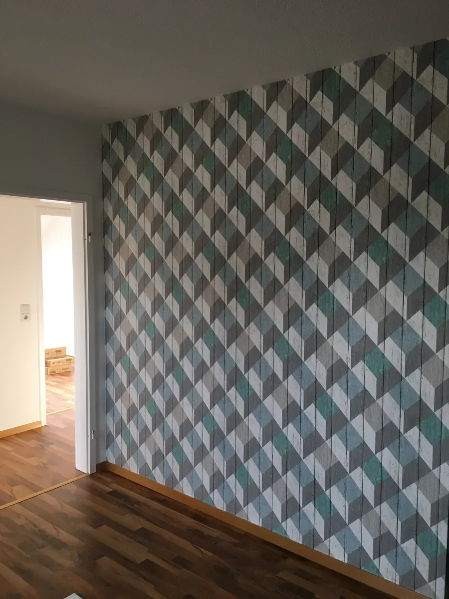 Zimmer mit Akzentwand in geometrisch gemusterter Tapete in Grau und Türkis – Malerbetrieb Mergenthaler im Saarland